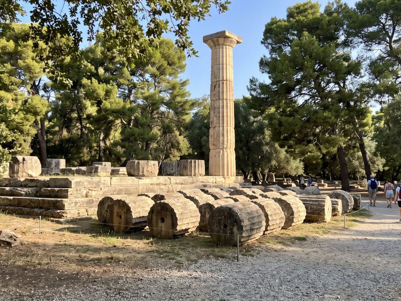 Resten van de tempel van Zeus in het oude Olympia met een weer opgerichte Dorische zuil tussen de pijnbomen