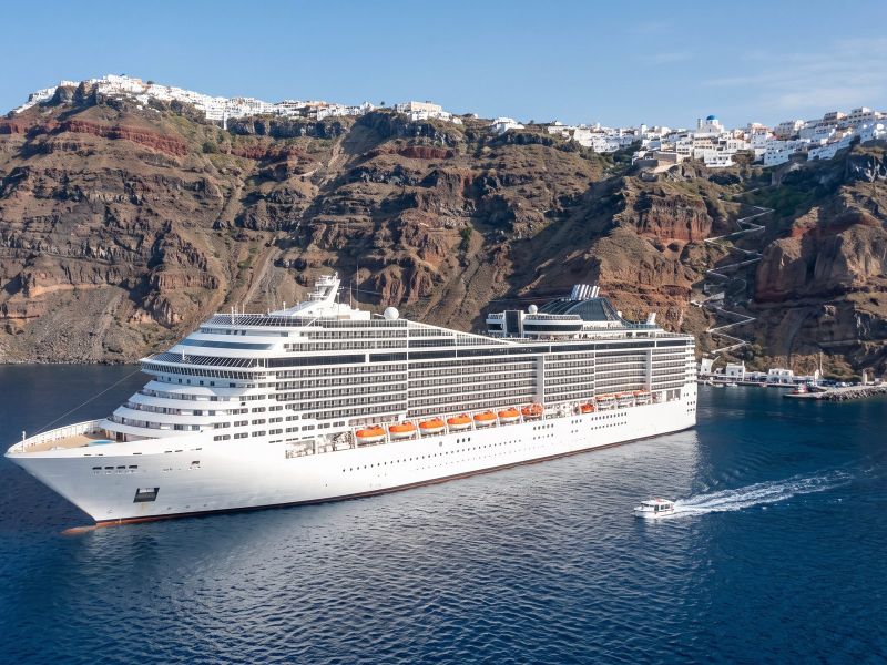 Groot modern cruiseschip voor anker in de caldera van Santorini, onder het witte stadje Fira boven op de klif